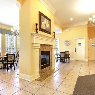 A cozy dining area featuring a central fireplace surrounded by tables and chairs, adorned with decorative art and elegant lighting.