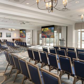 An empty conference room with rows of chairs facing multiple projector screens.