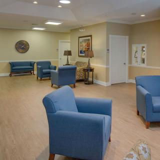 A spacious waiting area with comfortable blue chairs and warm lighting.