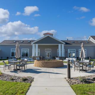 A modern building with a landscaped outdoor seating area under a partly cloudy sky.