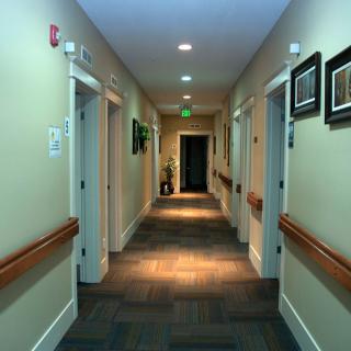 A well-lit hallway with multiple doors and framed artwork on the walls.