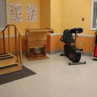 A physical therapy room equipped with a stationary bike and practice stairs.