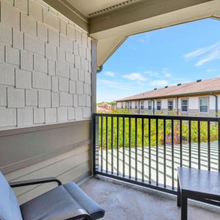 A cozy apartment balcony with chairs, offering a pleasant view of the surroundings under a clear blue sky.