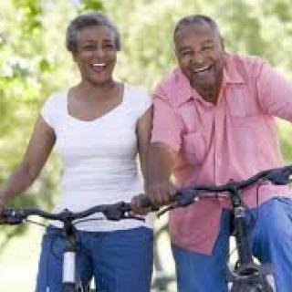 A smiling couple enjoying a bike ride outdoors.