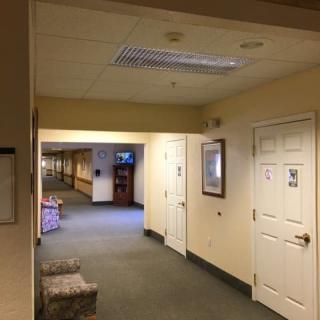 A well-lit hallway with multiple doors and a carpeted floor.