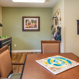 A cozy interior space featuring a table and chairs, with wall art and decorative elements.