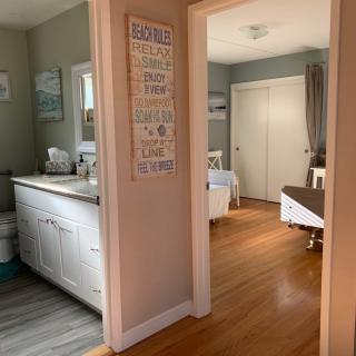 A cozy home interior featuring a connected bathroom and bedroom with warm wooden flooring.