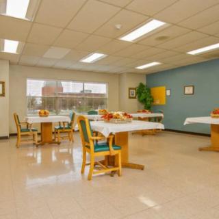 An empty dining room with neatly arranged tables and chairs, illuminated by ceiling lights.