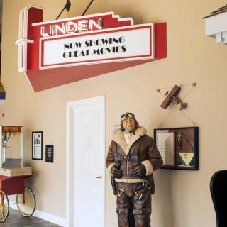 A vintage movie theater theme with a classic marquee sign, an aviator mannequin, and a popcorn machine.