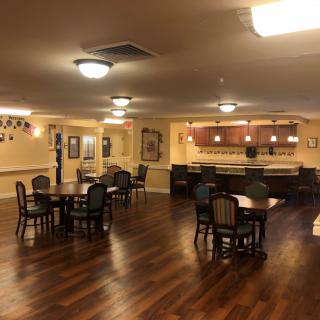 A spacious dining area with several tables and chairs, featuring a bar in the background.