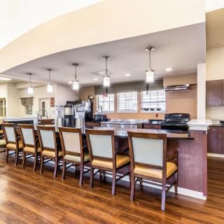 A modern kitchen with a bar area featuring multiple chairs and pendant lighting.