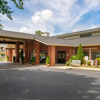 A hotel entrance with a covered driveway and well-maintained landscaping.