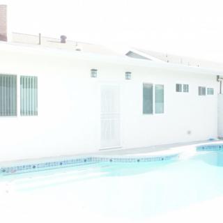 A bright outdoor shot of a house with a swimming pool.