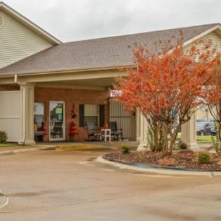 A building entrance with autumn-colored trees and a covered porch.