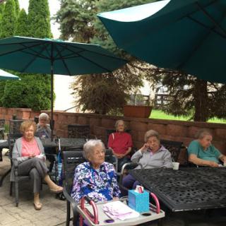 A group of seniors enjoying a sunny day outdoors under umbrellas.