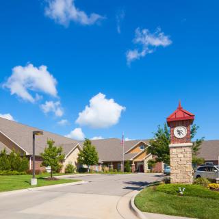 A residential area featuring a clock tower under a clear blue sky with scattered clouds.