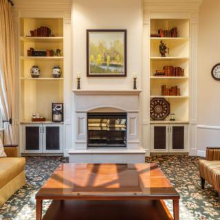 A cozy living room features a central fireplace flanked by built-in bookshelves, with a wooden coffee table and comfortable seating.