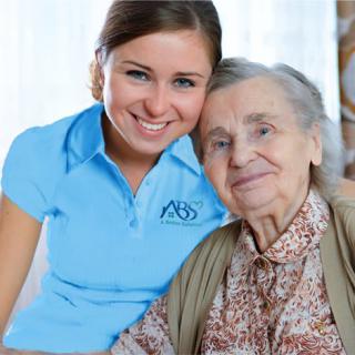 A caregiver smiling with an elderly woman, representing companionship and support in a healthcare setting.