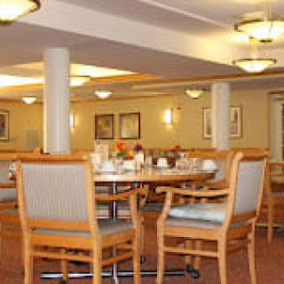 A cozy dining area with neatly arranged tables and chairs, softly lit by ceiling lights.