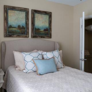 A cozy bedroom with a neatly made bed, accented by decorative pillows and framed artwork above the headboard.