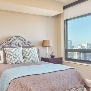 A cozy bedroom with a large window offering a cityscape view.