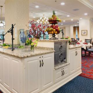 A well-decorated kitchen and dining area featuring a central countertop adorned with flowers and a fruit display.