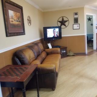 A cozy living room featuring a leather sofa, decorative wall art, and a television setup.