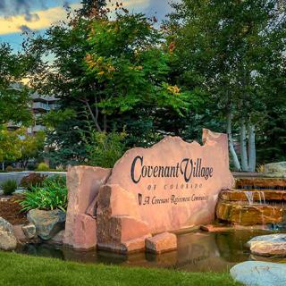 A scenic view of a stone sign for Governor's Village, surrounded by lush greenery and a water feature.