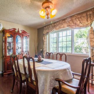 A well-lit dining room with a large table, chairs, and a china cabinet by the window.