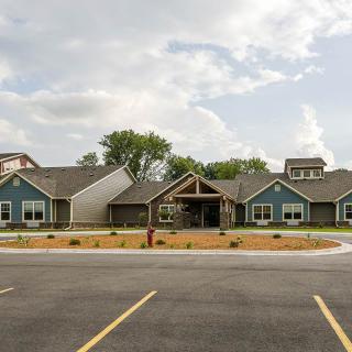A modern residential building with a landscaped driveway under a partly cloudy sky.