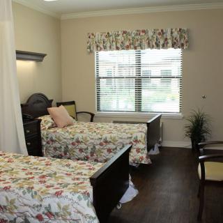 A cozy bedroom with two twin beds, floral bed covers, and a window letting in natural light.