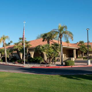 A building with palm trees and a well-maintained entrance under a clear blue sky.