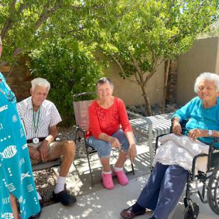 A group of seniors enjoying a sunny afternoon outdoors, engaged in conversation.
