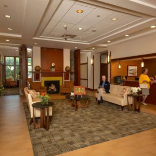 A hotel lobby with comfortable seating and a fireplace, featuring two people relaxing.
