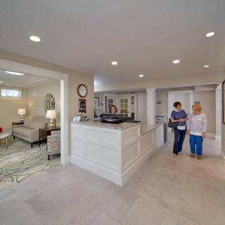 A modern reception area with elegant furniture and two people walking through.