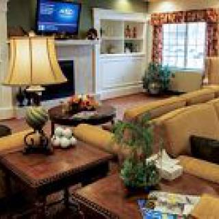A cozy living room featuring a beige sofa, decorative lamps, a fireplace, and a mounted television.