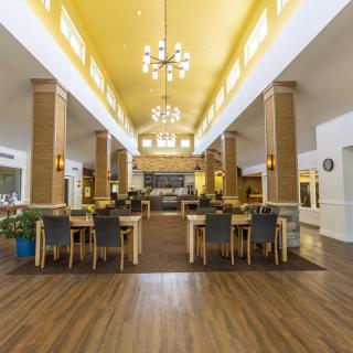 A spacious dining area with modern decor, featuring chandeliers and wooden flooring.