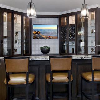 A stylish home bar featuring modern seating, elegant lighting, and well-organized cabinets.
