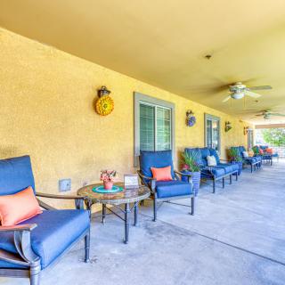 A cozy outdoor patio with blue cushioned chairs and small tables against a yellow wall.