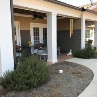 A cozy patio area with chairs and a table next to a landscaped pathway.