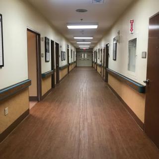 A view of a well-lit hospital hallway with doors on either side.