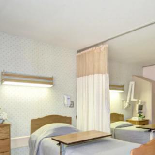 A hospital room with a single bed and a privacy curtain.