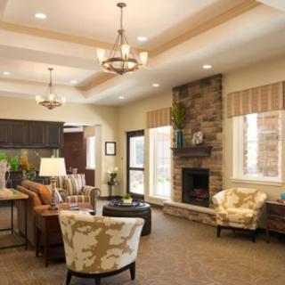 A modern living room with stylish furniture and a stone fireplace, featuring decorative ceiling lights.