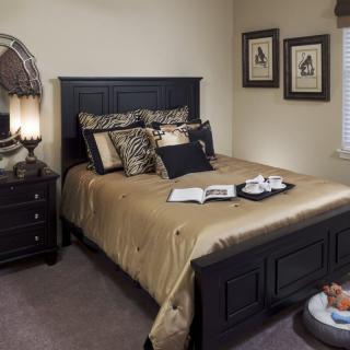 A cozy bedroom with elegant dark furniture and decorative pillows.
