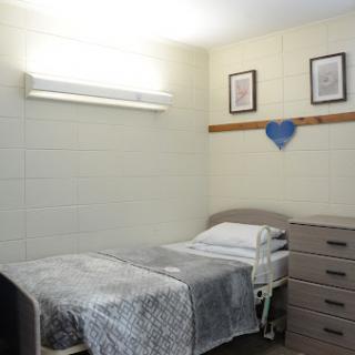 A simple hospital room featuring a bed, storage drawers, and minimal decor.