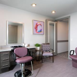 A modern salon interior with stylish chairs, a mirror, and vibrant artwork on the wall.