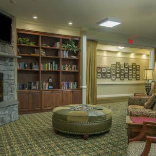 A cozy living room with a large bookshelf and stone fireplace.
