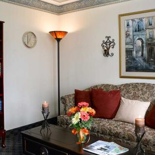 A cozy living room with a floral sofa, decorative cushions, and a well-lit lamp.