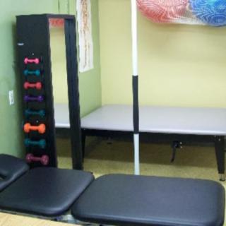 A physical therapy room equipped with dumbbells and exercise mats.