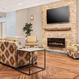 A modern lobby with a cozy seating area, featuring a fireplace and television.